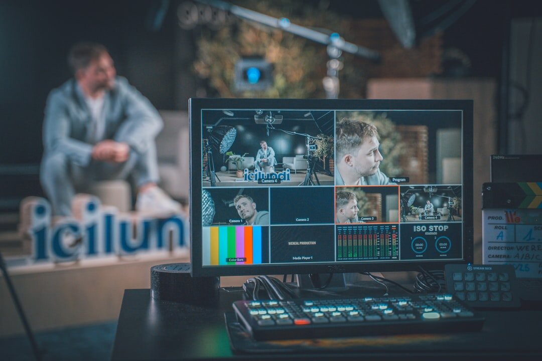 Journalist monitoring multiple video news feeds on screens in a control room
